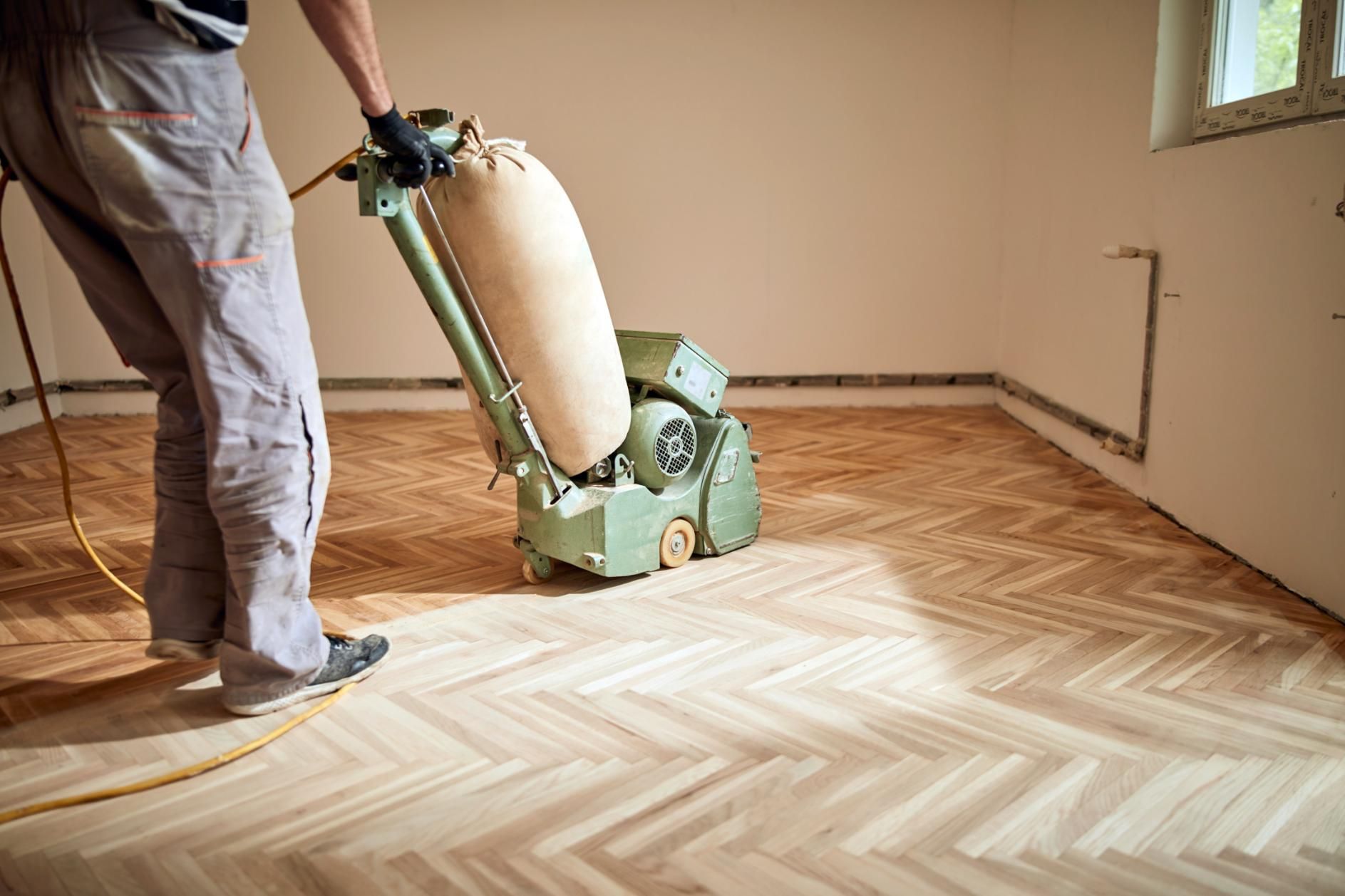 A Man is Sanding a Wooden Floor With a Machine — Norwood Floor Sanding in Ballina, NSW