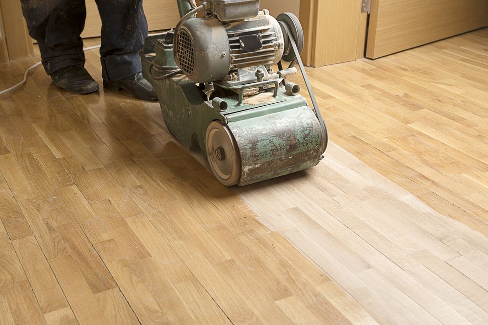 A Person is Sanding a Wooden Floor With a Machine — Norwood Floor Sanding in Ocean Shores, NSW