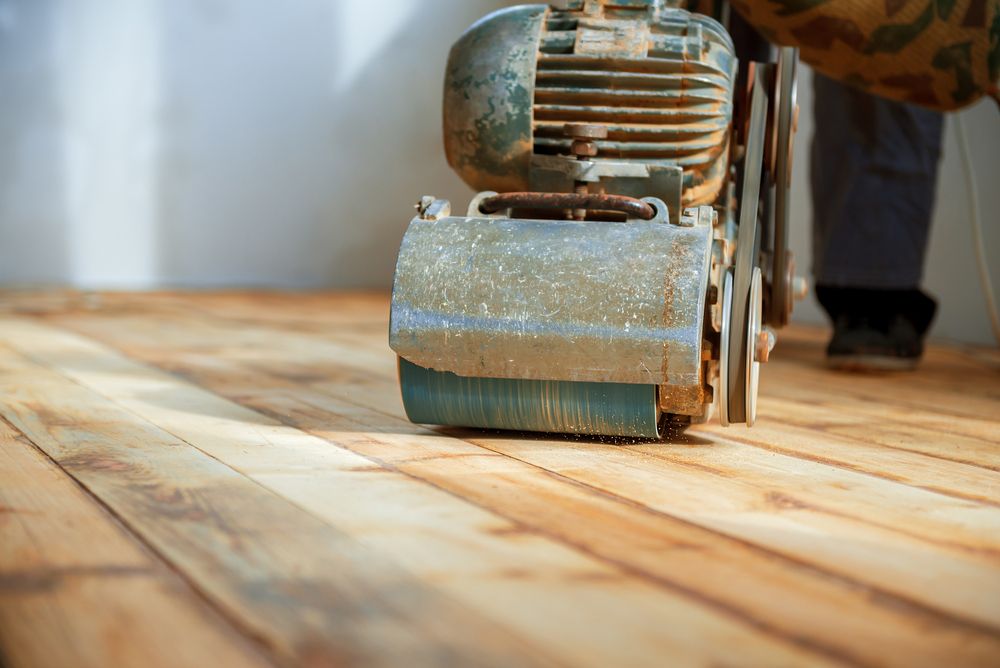 A Person is Sanding a Wooden Floor With a Machine — Norwood Floor Sanding in Murwillumbah, NSW