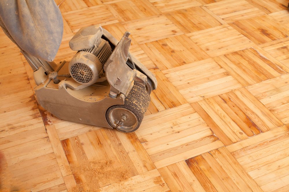 A Person is Sanding a Wooden Floor With a Machine — Norwood Floor Sanding in Lennox Head, NSW