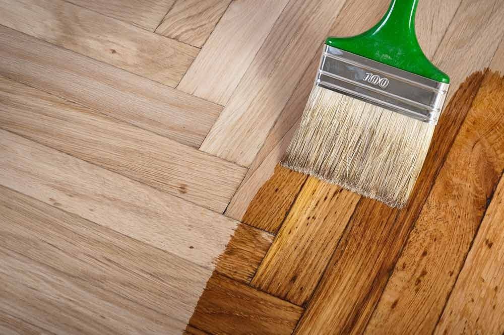 A Brush is Being Used to Paint a Wooden Floor — Norwood Floor Sanding in Ocean Shores, NSW