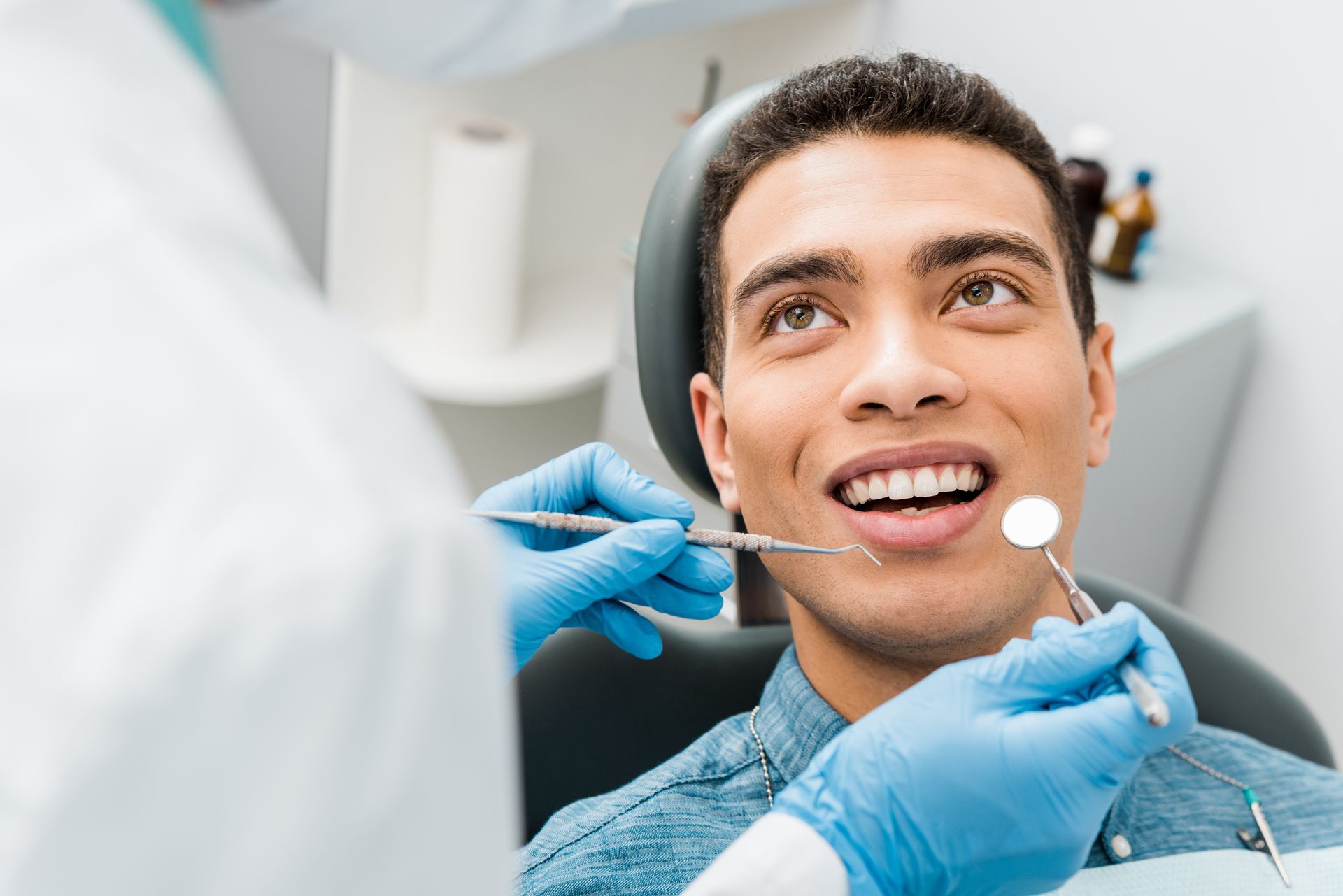 A cheerful man and a dentist holding instruments during an examination in a dental clinic.
