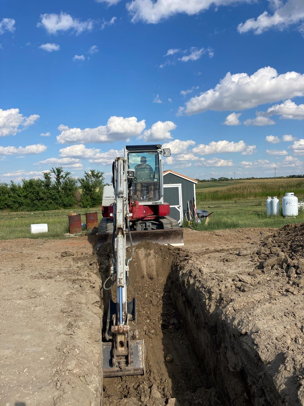 An excavator is digging a hole in the dirt in a field.