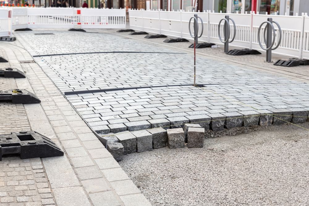 A brick sidewalk is being built on a city street.