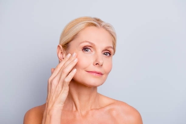 A woman is touching her face with her hand and looking at the camera.