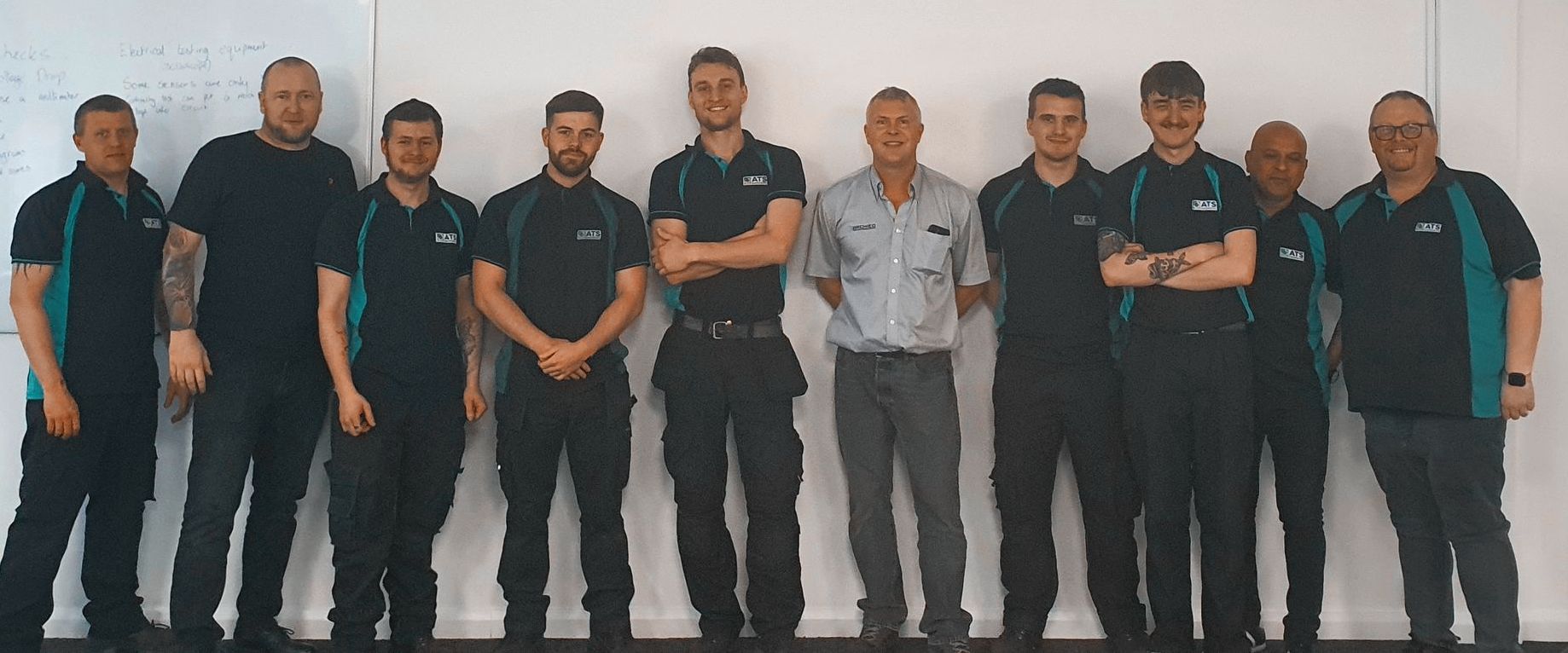 A group of men standing next to each other in front of a white wall.