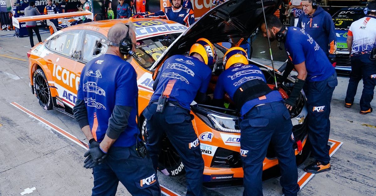 A group of men are working on a race car in a pit lane.