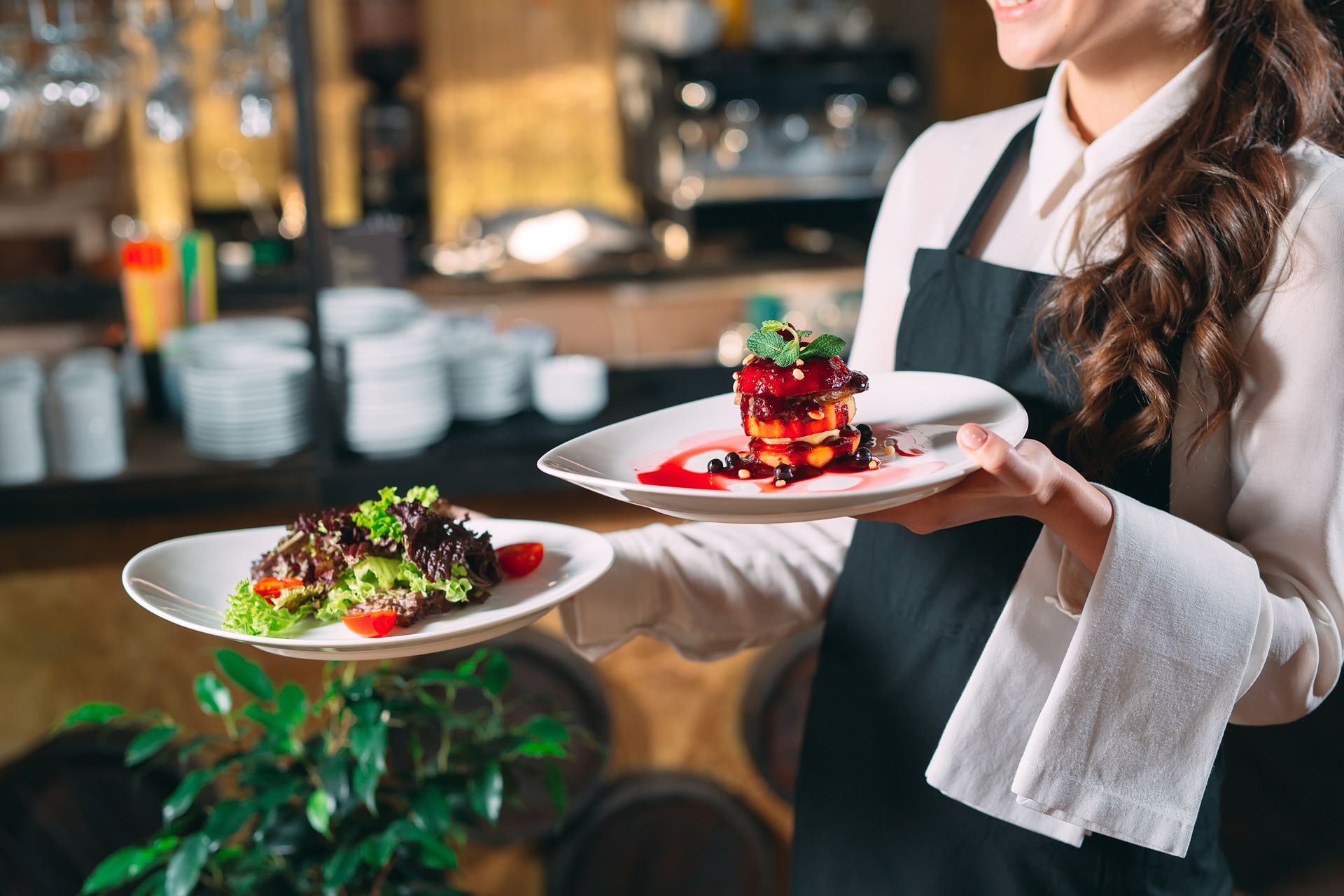 Reserved sign on a wooden restaurant table beside silverware and wine glasses, with a blurred dining background