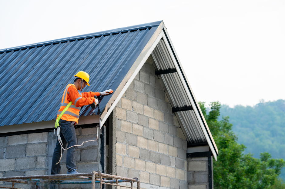 A construction worker is installing a metal roof on a house.