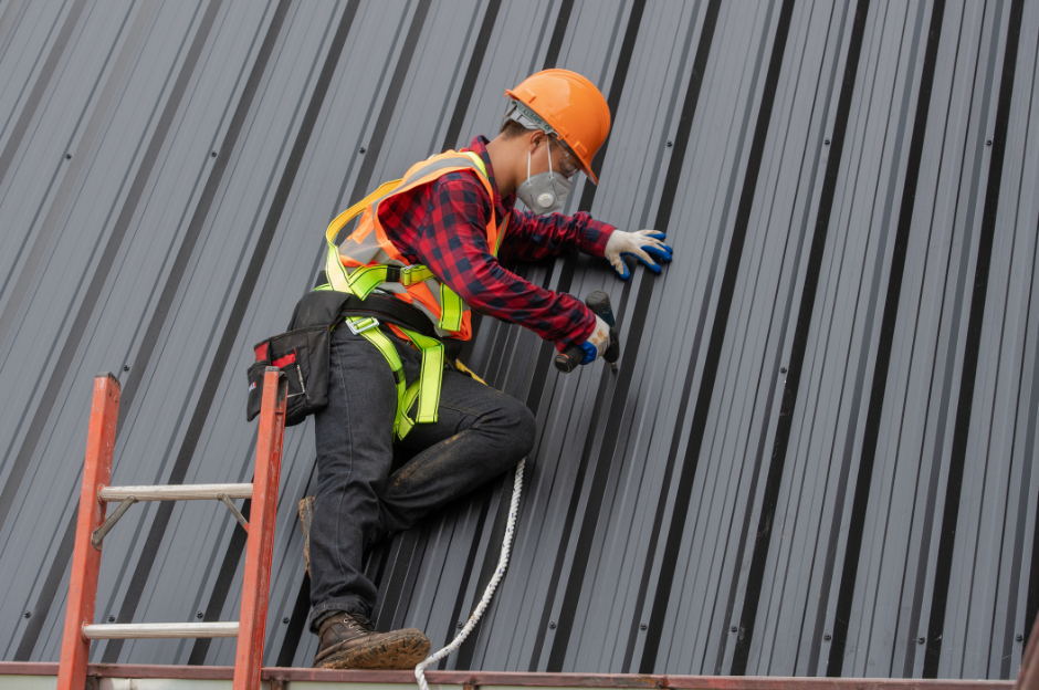 A man is standing on a ladder working on a roof.