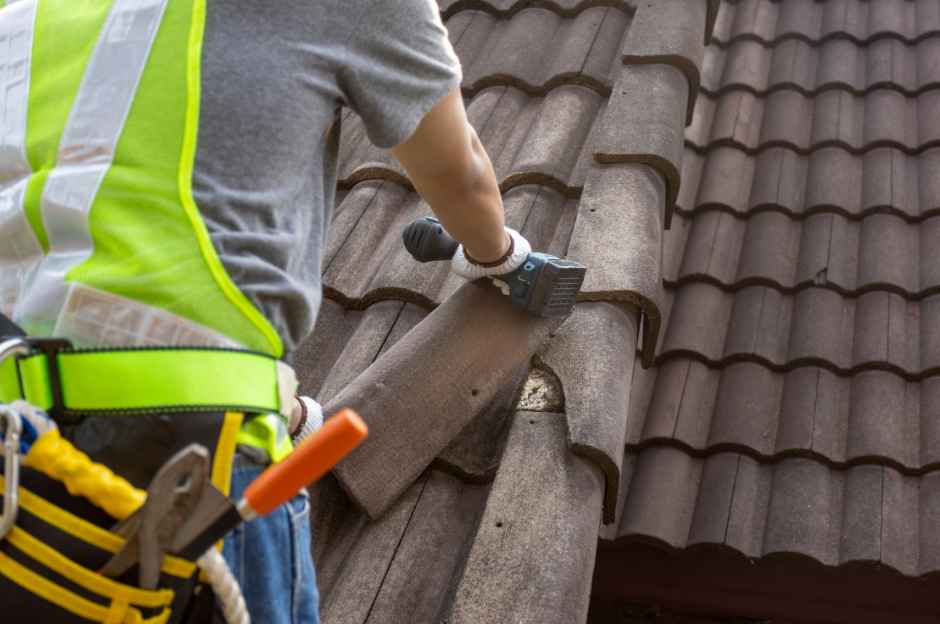 A man is working on a roof with a saw.