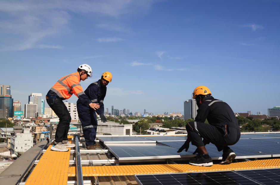 Three men are working on a roof with solar panels.