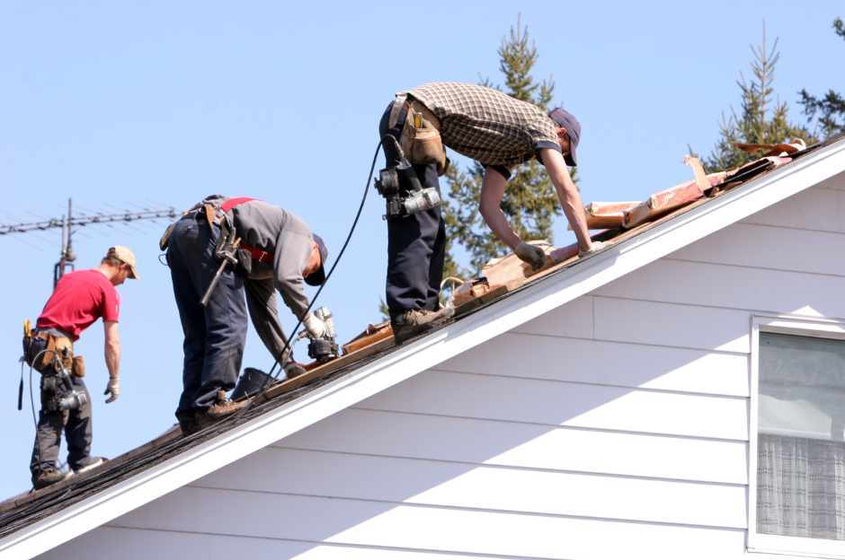Three men are working on the roof of a house.