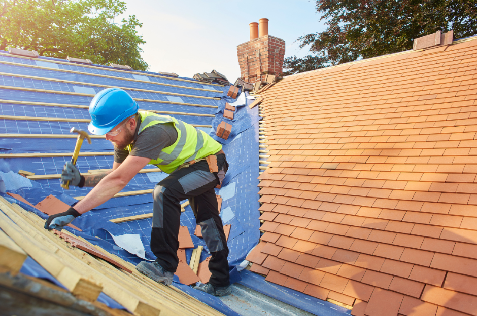 A man is working on a roof with a hammer.