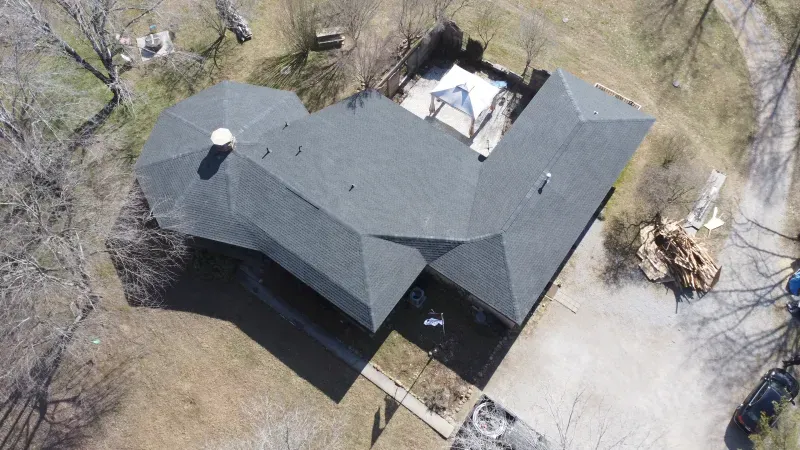An aerial view of a house with a black roof and a patio.