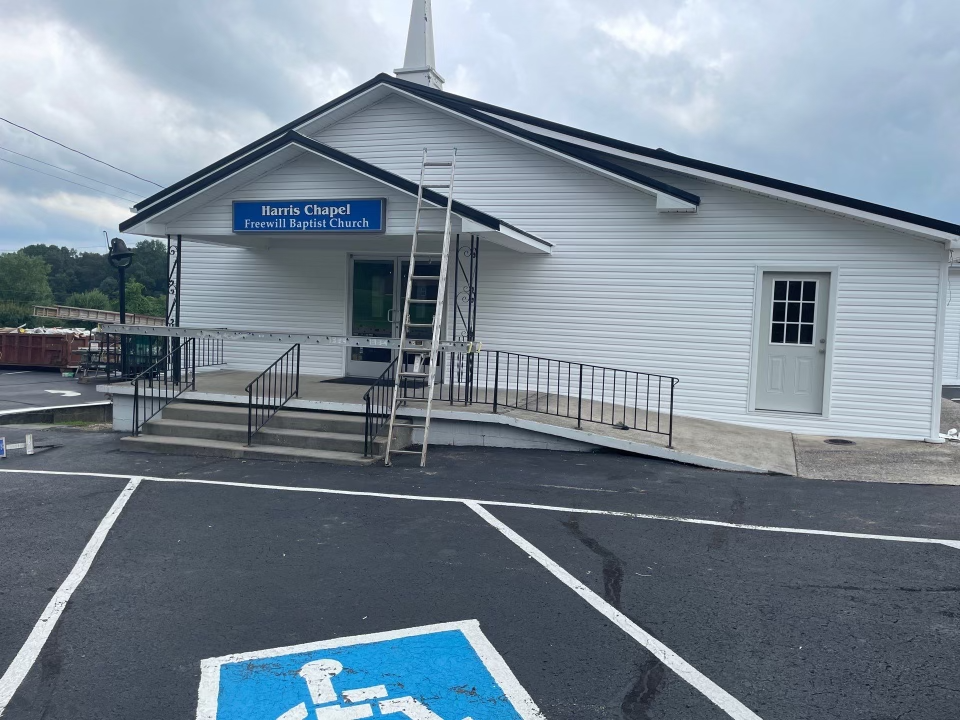 A white building with a handicapped parking spot in front of it.