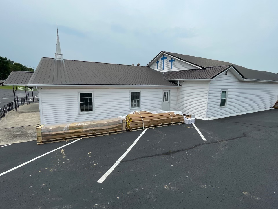 A white building with a brown roof and two crosses on it