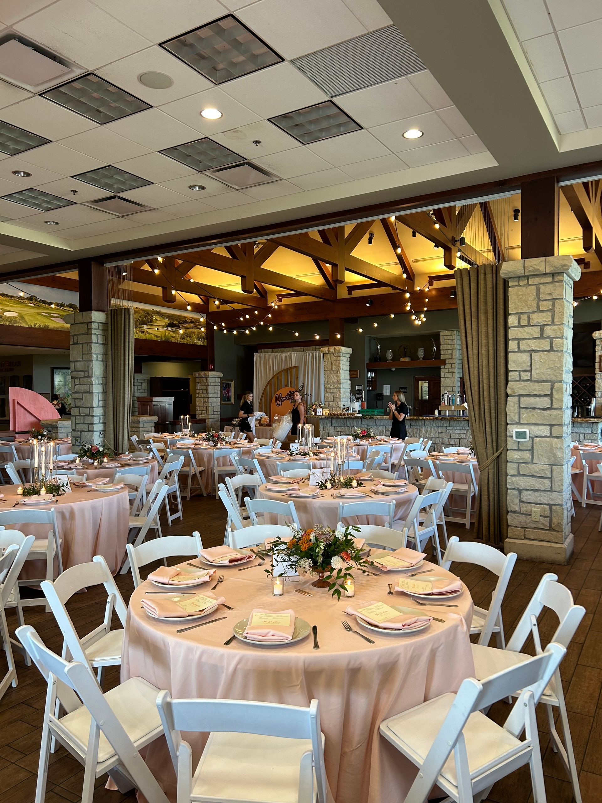 A large room with tables and chairs set up for a wedding reception.
