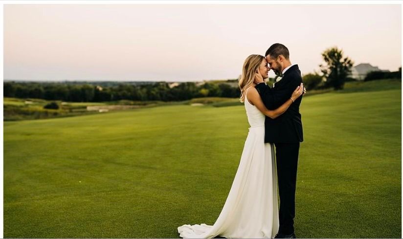 A bride and groom are posing for a picture on a golf course.