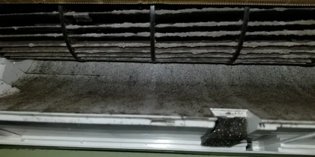 Un conduit de climatisation sale est couvert de crasse et de poussière.