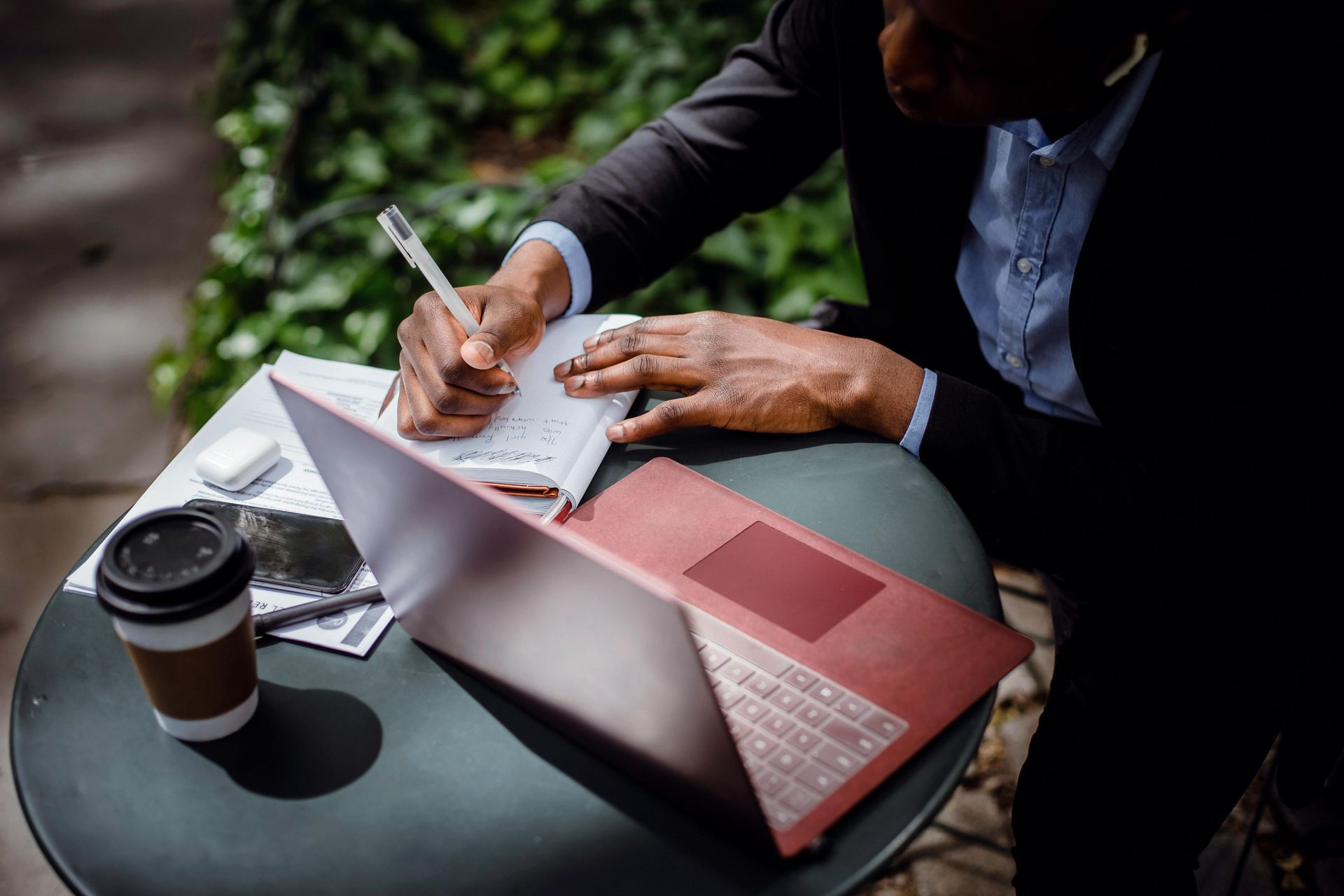man aan het werk op laptop met notitieblokje
