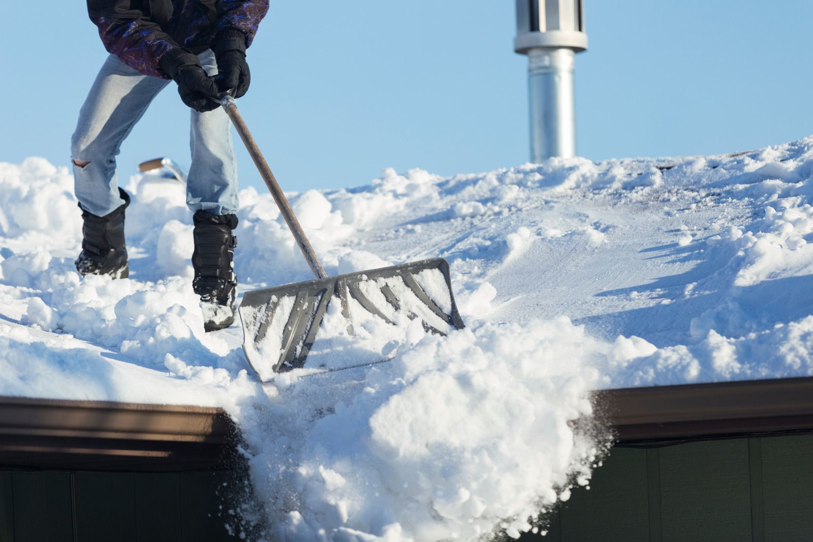 A man is blowing snow from a snow blower on a snowy field.