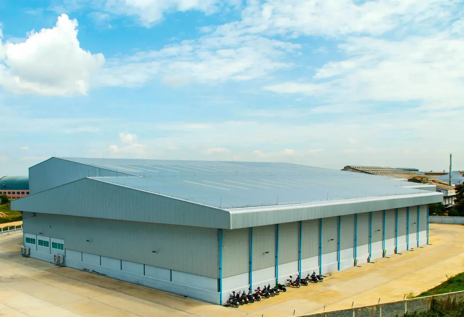 An aerial view of a large warehouse with motorcycles parked in front of it.