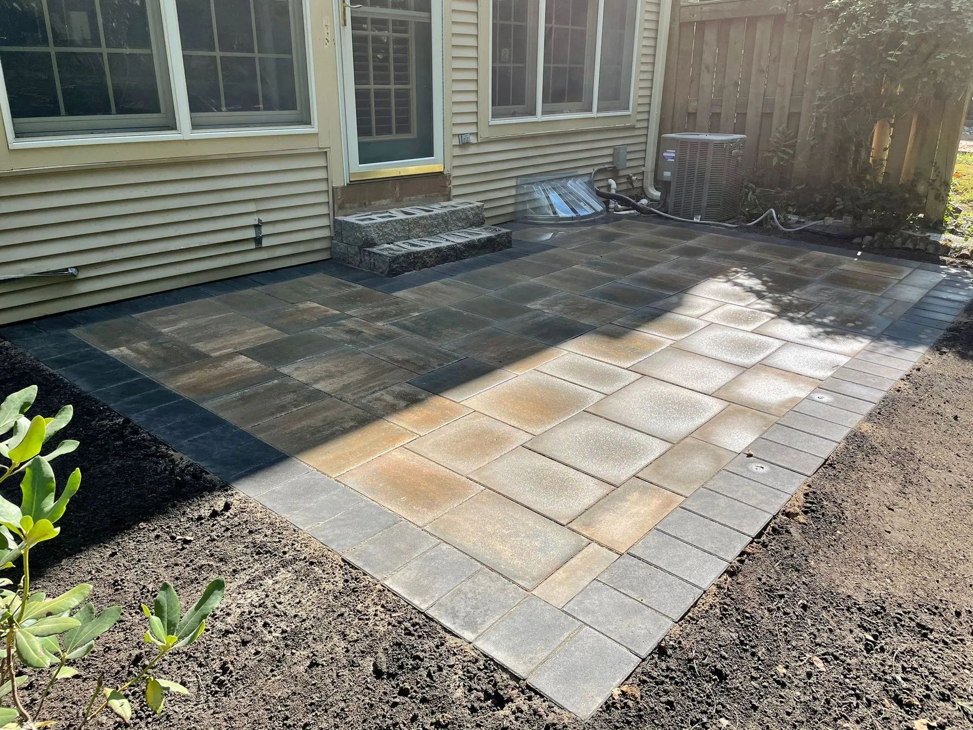 A patio is being built in the backyard of a house.
