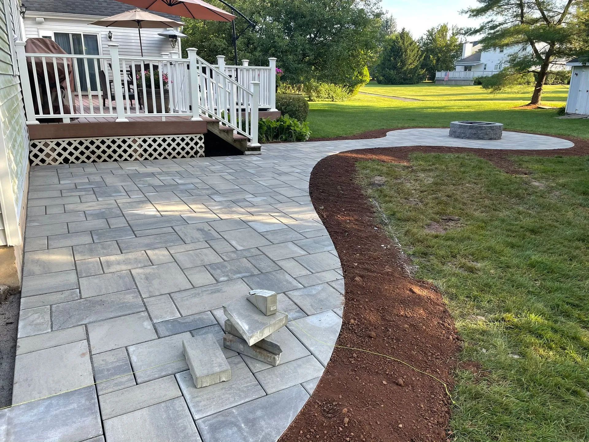 A patio with a deck and a fire pit in the backyard.