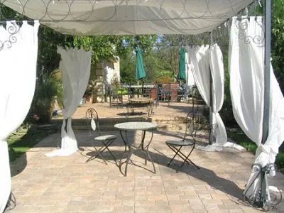 A patio with a table and chairs under a canopy with white curtains.