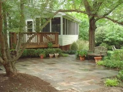 A house with a screened in porch and a stone patio