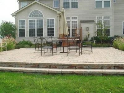 A patio with a table and chairs and an umbrella in front of a house
