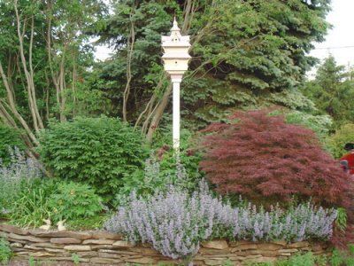 A white birdhouse is in the middle of a garden