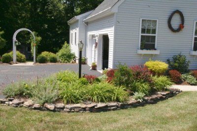 A white house with a garden in front of it and a wreath on the wall.