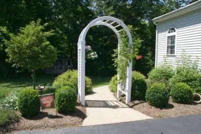 A white archway leading to a white house