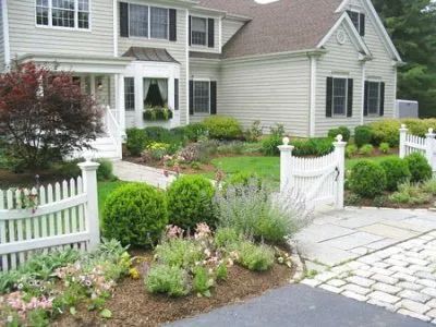 A white picket fence is in front of a house