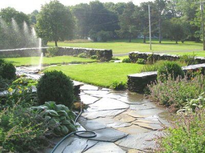 A hose is connected to a stone walkway in a garden