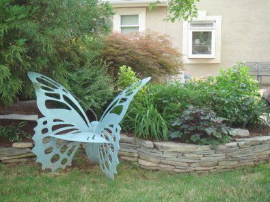 A butterfly statue is sitting in the grass in front of a house.