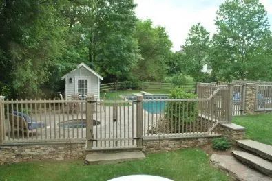 A fence surrounds a swimming pool in a backyard.