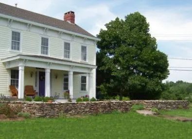 A large white house with a stone wall in front of it