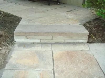 A stone walkway with steps leading up to a stone wall.