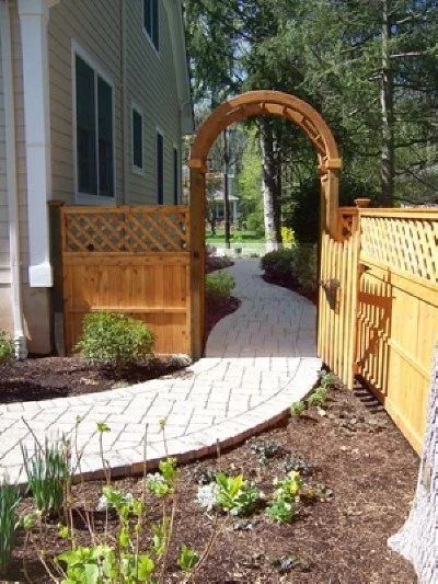 A wooden fence surrounds a walkway leading to a house.