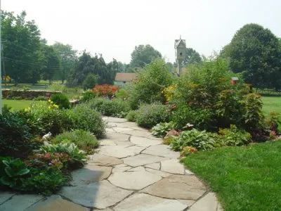 A stone walkway in a garden with a tower in the background