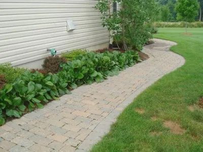 A brick walkway going to the side of a house