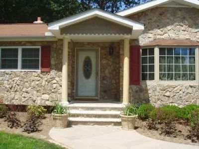 A stone house with a white door and red shutters