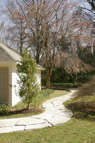 A path leading to a white house with trees in the background