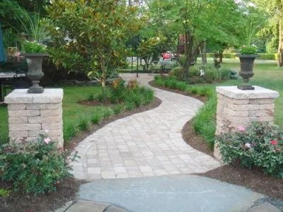 A brick walkway leading to a patio in a garden