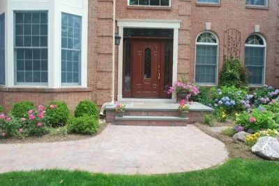 A brick house with a wooden door and a brick walkway leading to it.