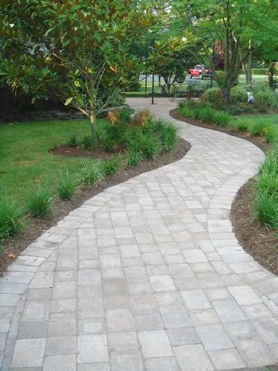 A brick walkway going through a lush green garden.
