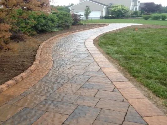 A brick walkway leading to a house in a residential area.